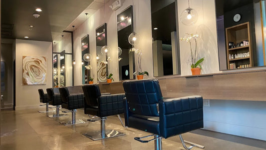 The styling row at Whistle & Sway Salon Company in Fort Worth, black chairs and lit mirrors along the color bar