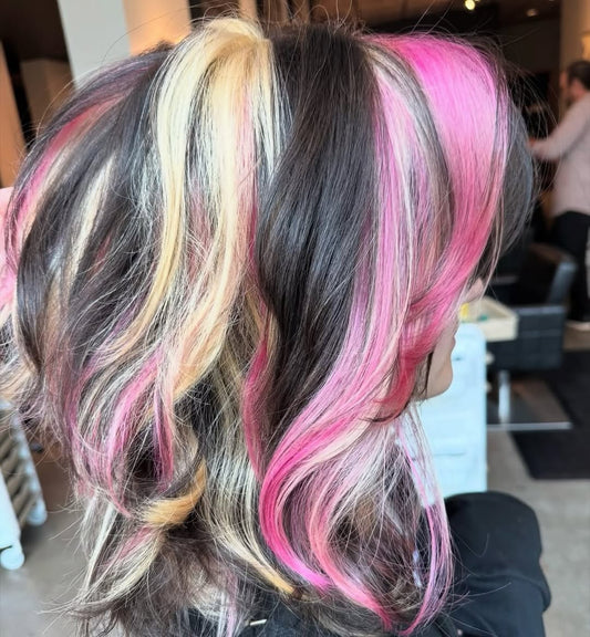 Chunky pink and blonde dimensional color placed through dark hair at Whistle & Sway Salon Company in Fort Worth